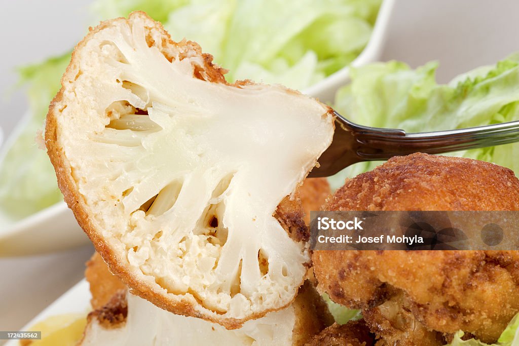 Lunch with fried cauliflower Fried cauliflower with potatoes and lettuce on plate. Selective focus, shallow DOF. Beige Stock Photo