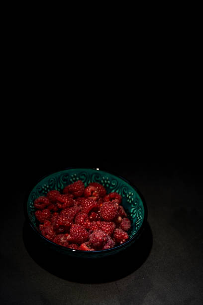 Raspberries in a plate on a dark background Top view