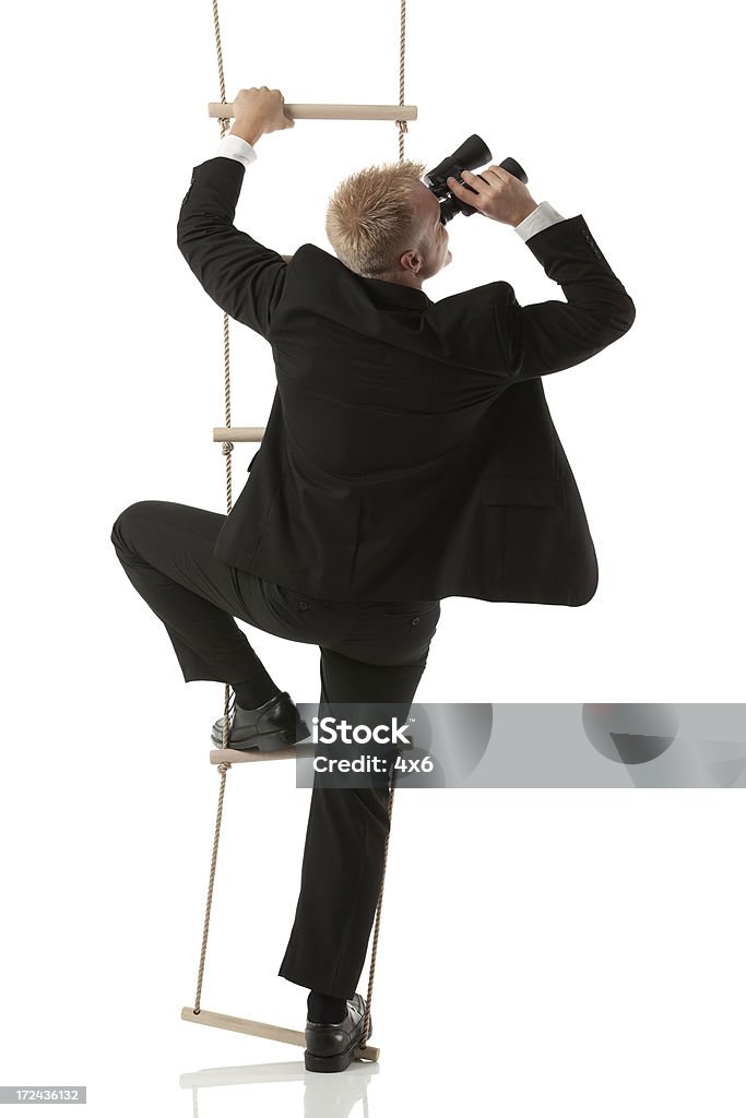 Uomo d'affari su scala alla ricerca attraverso il binocolo - Foto stock royalty-free di Abbigliamento elegante