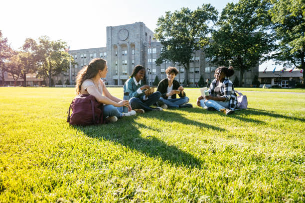 istock Group of diverse students in campus outdoors, sitting on lawn and enjoying snack after lectures 1724366018