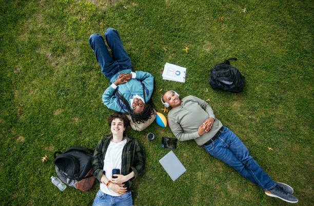istock High angle view of group of diverse students in campus outdoors, lying on grass and talking 1724366572