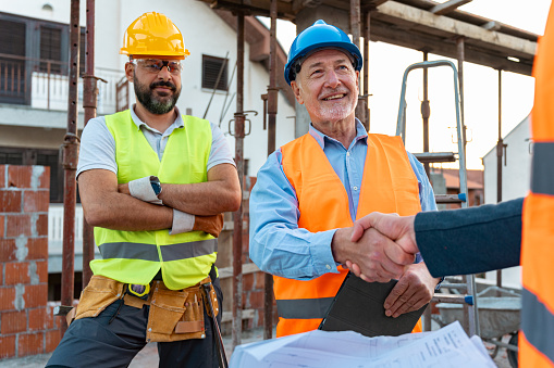 During an meeting, senior male Caucasian engineer, handshake with an architect on a construction site