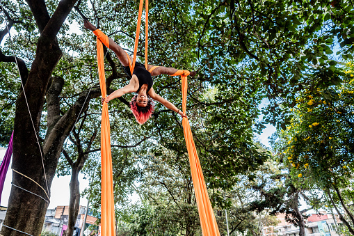 Gymnast practicing aerial silk exercises at the public park