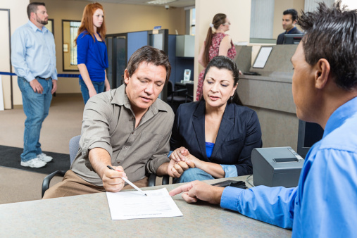 A mature couple receives an application at a bank.