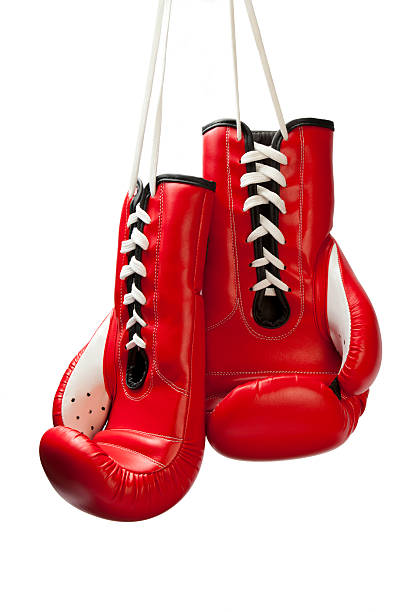 Close up pair of red leather boxing gloves hanging over black wall with copy space
