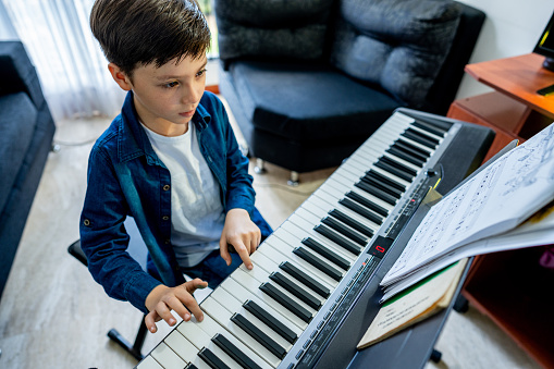 Boy playing synthesizer at home