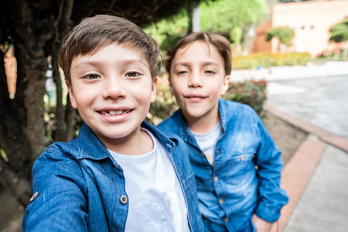 Twin brothers taking a selfie outdoors - camera point of view