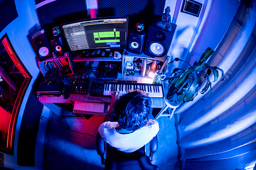 High angle view of a man playing keyboard to do a music or remix at music studio