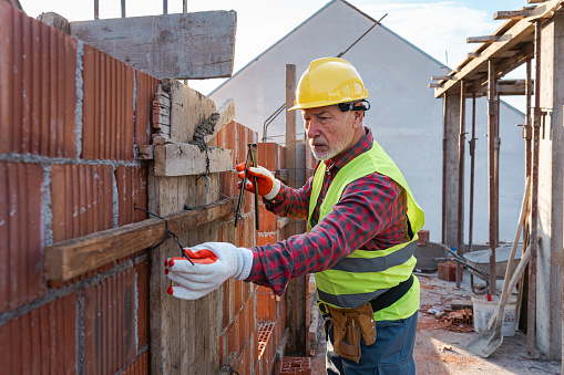 industrial bricklayer worker placing bricks on cement while building exterior walls, industry details