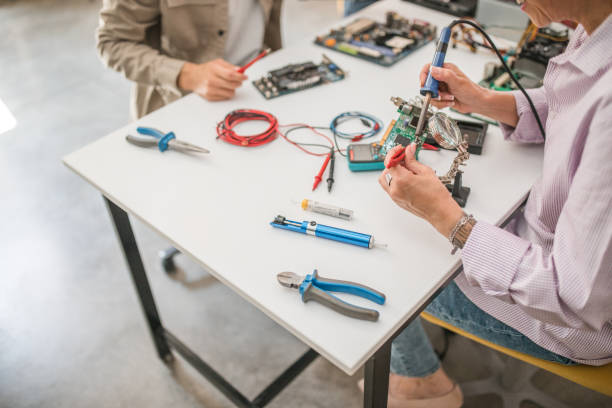 istock Close-up of the hands of a professor using an electrical measuring instrument while doing electronics exercises with a group of students 1724393093