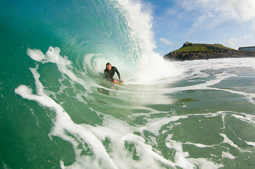 A young man bodyboarding a powerfully wave on the north Cornwall coast on a sunny day.