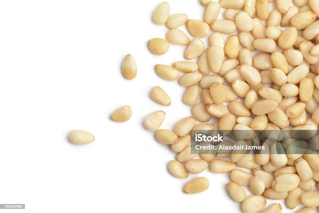 Pine nuts scattered Pine nuts scattered across a white background. Pine Nut Stock Photo