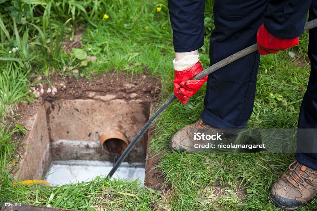 Homme débloquant une drain-Expression anglo-saxonne - Photo de Système d'écoulement des eaux libre de droits