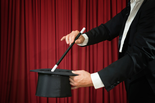 Magician with top hat and magic wand, performing on stage