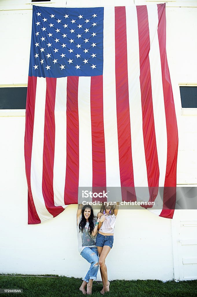 Bela jovem mulher em pé por uma bandeira americana contra a parede - Foto de stock de Descalço royalty-free