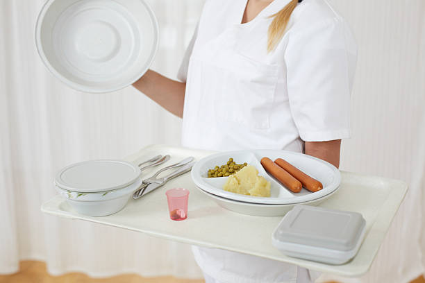 Top view of plastic food tray placed on bed with clean white sheet in hospital room