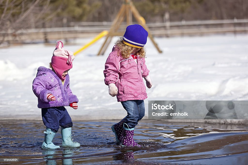 Dziewczęta grają w Spring Kałuża - Zbiór zdjęć royalty-free (Śnieg)