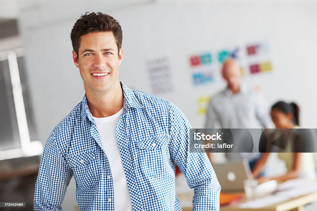Leading his team into design stardom Portrait of a confident young designer smiling for the camera with colleagues working in the backgroundhttp://195.154.178.81/DATA/istock_collage/0/shoots/784914.jpg Adult Stock Photo