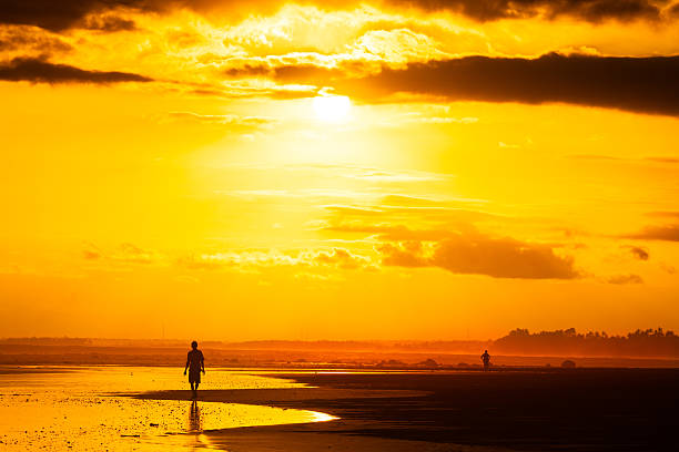 Man walking along the beach at sunset