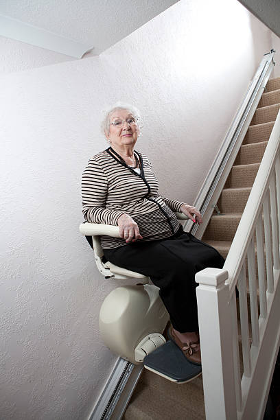 Senior lady who has mobility issues uses a Stair Lift stock photo