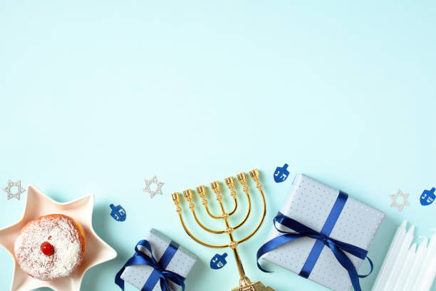 istock Happy Hanukkah banner template. Flat lay gold menorah, jelly donut, candles, gift boxes on pastel blue background. Jewish holiday elements top view. 1724428607