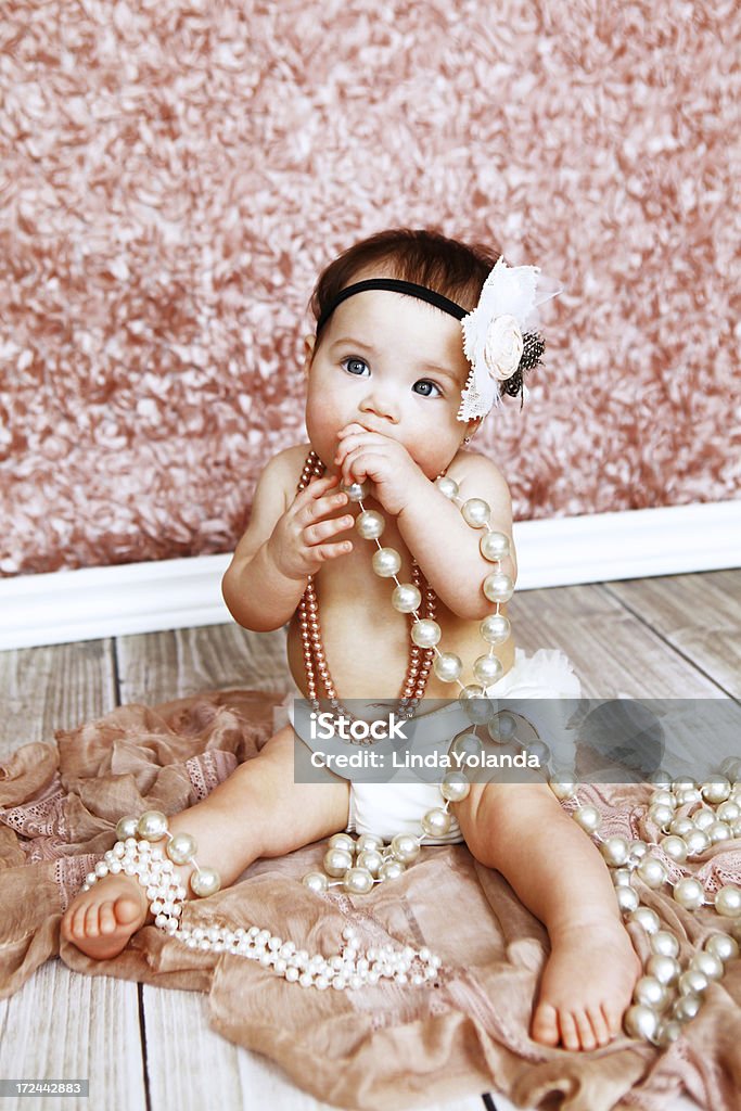 Baby Girl Wearing Pearls A portrait of a beautiful baby girl wearing pearls and a pretty hairband. She is nine months old. Soft focus. Vintage inspired image. 6-11 Months Stock Photo