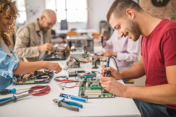 istock Working atmosphere in an electronics class where a small group of students learn about computer hardware and how to use a soldering iron and repair broken computer parts 1724430269