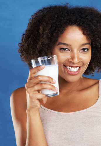 A health conscious woman enjoying a glass of milk while isolated on a white background