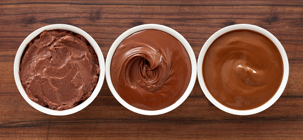 Three bowls containing soft chocolate stuff (mousse, spread and pudding)