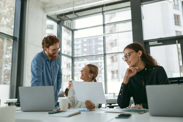 istock Group of business people discussing something and smiling while sitting at the office table 1724440377
