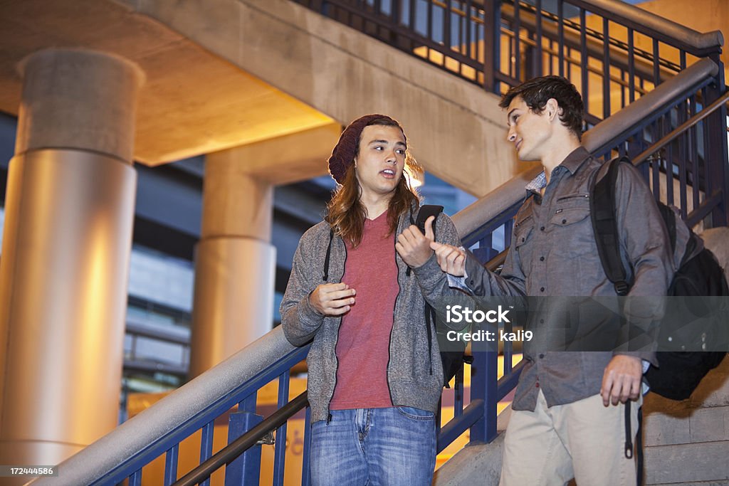 Teenage friends going down stairs Teenage boys (18 years) talking and walking down stairs (exiting train station). Candid Stock Photo