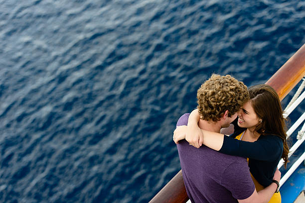 Young happy couple on a cruise ship Young couple looking at each other romantically over cruise ship railing with ocean. cruising stock pictures, royalty-free photos & images