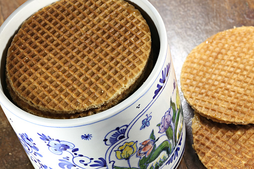 traditional Dutch syrup waffles in an original Delftware container on wooden background