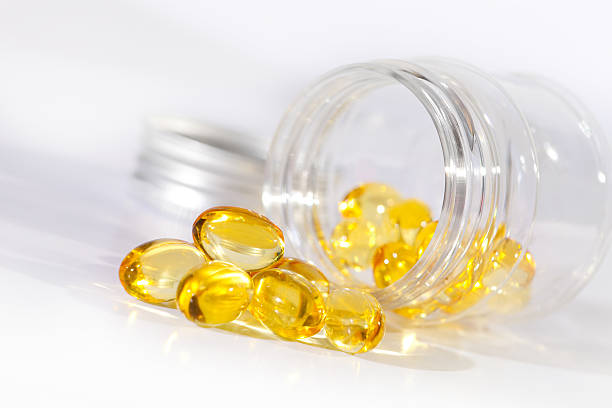 close-up of витамин гель таблетки, выходящими из медицины бутылки - gel effect capsule fish oil pill стоковые фото и изображения