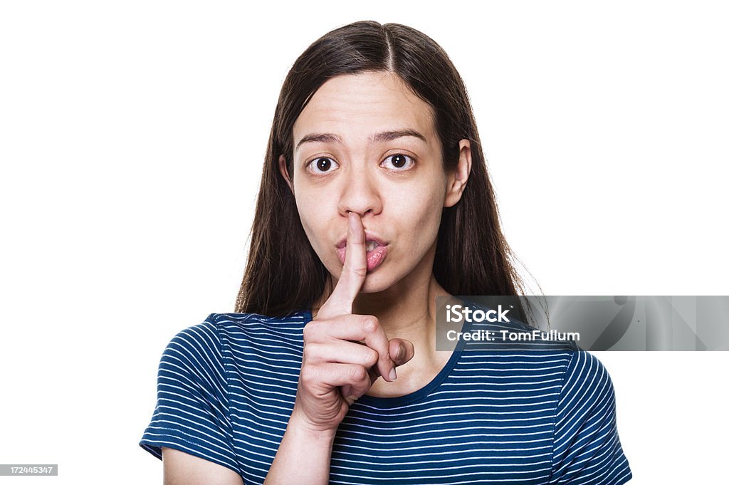 Woman Saying Shhhh Young woman with finger in front of mouth against white background. 25-29 Years Stock Photo
