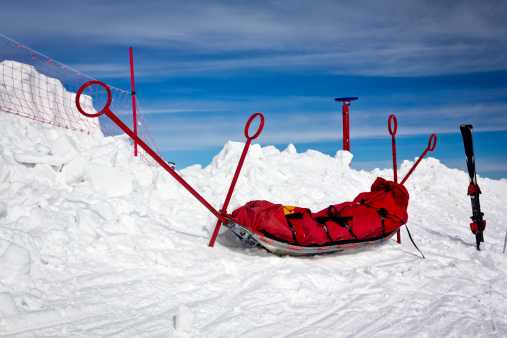 Ski and empty mountain rescue sled over snow in the mountains