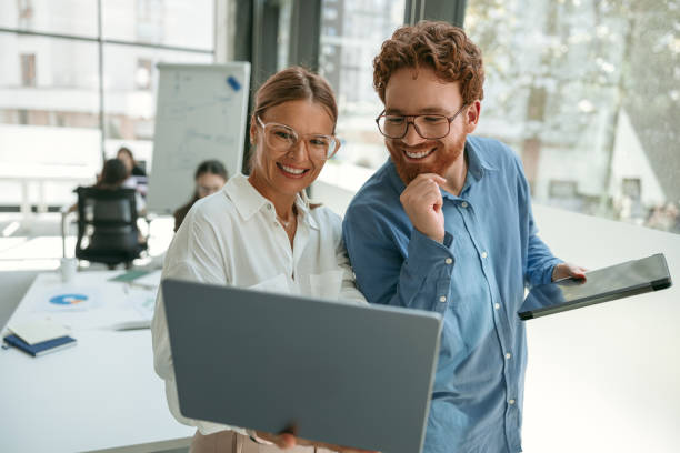 istock Two smiling business colleagues working together on project in office while use laptop 1724457384