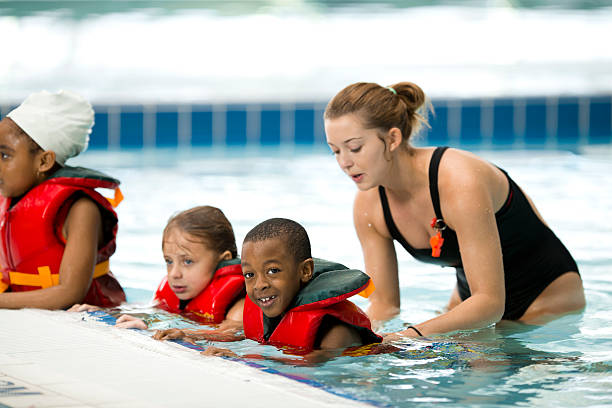Swimming Lessons Little kids learning to swim women exercising swimming pool young women stock pictures, royalty-free photos & images