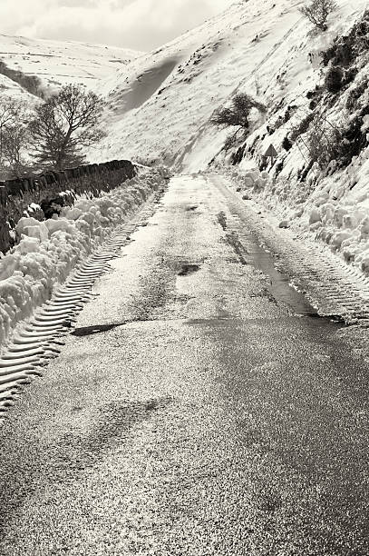 schmale landstraße zwischen hügeln im schnee am wintertag - road isweather2012 weather country road stock-fotos und bilder