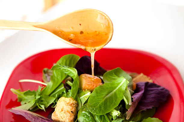 Food:  Green salad with dressing pouring on top from spoon  Healthy lifestryle eating.