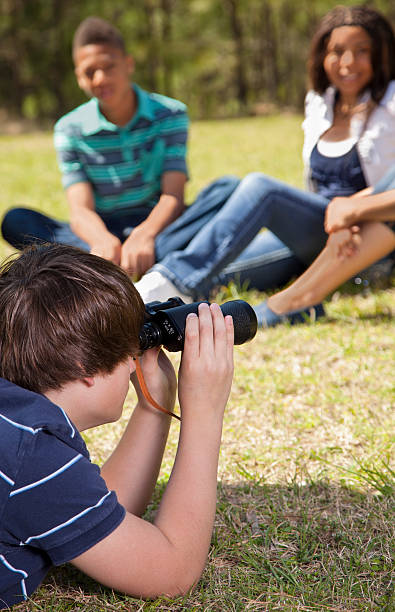 istock Teenagers: Park spectators.  One looking with binoculars in distance 172446613