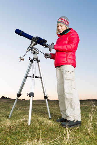 Female amateur astronomer adjusting her three inch refracting telescope at sunset in readiness for an evenings skyviewing. AdobeRGB colorspace. More astronomy themes in this lightbox::