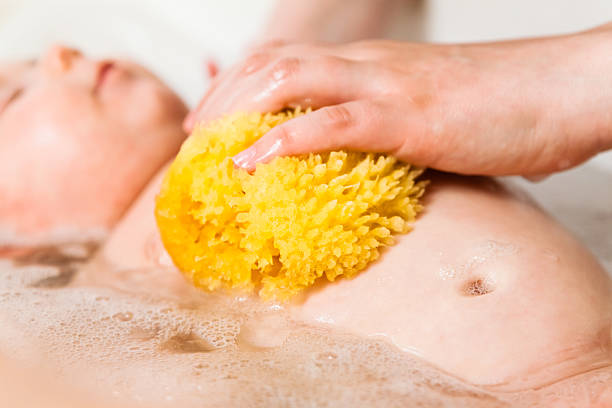 Bathing a two months old baby. Natural sponge.