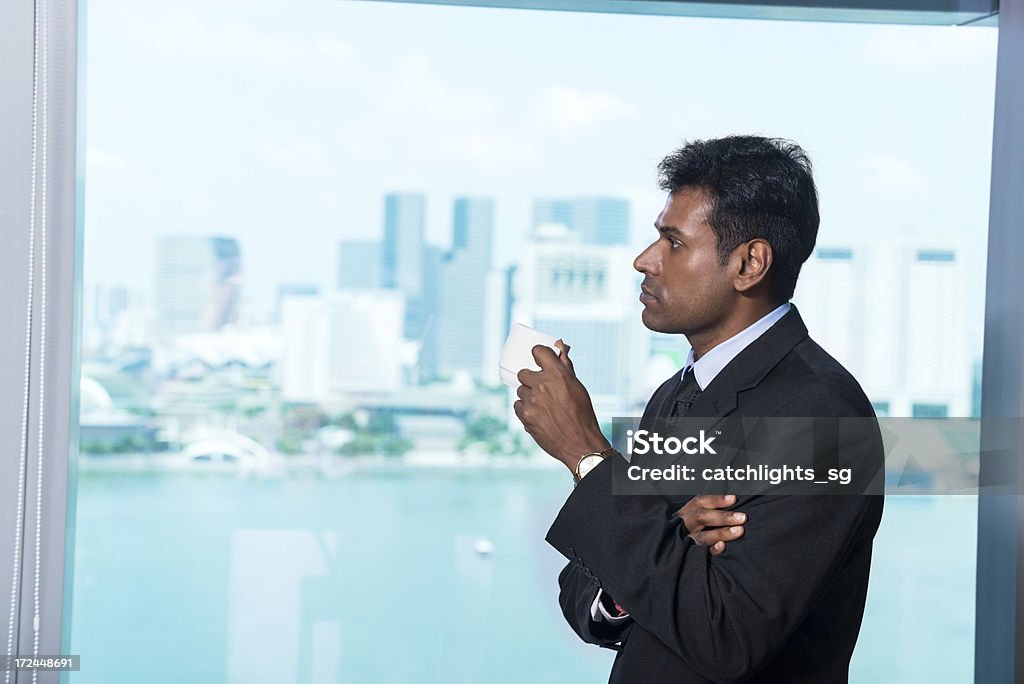 Asian businessman Asian Indian businessman drinking from a cup against windows of city view. 30-34 Years Stock Photo