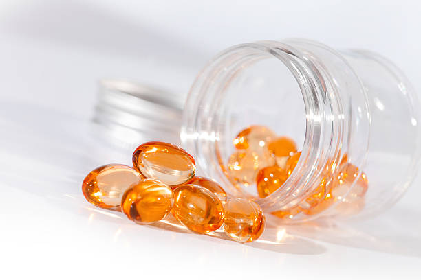 nahaufnahme des vitamin-gel tabletten aus medizin-flasche heraus. - capsule gel effect pill vitamin pill stock-fotos und bilder