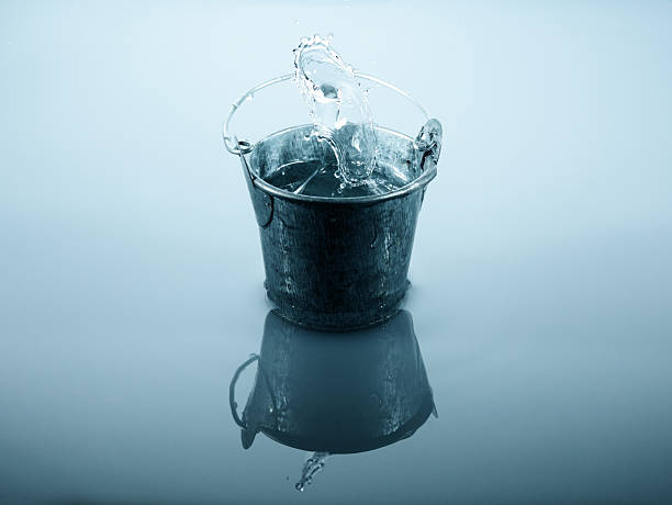 water bucket "Metal bucket with splashing water , studio shot using high speed technique." watering pail stock pictures, royalty-free photos & images