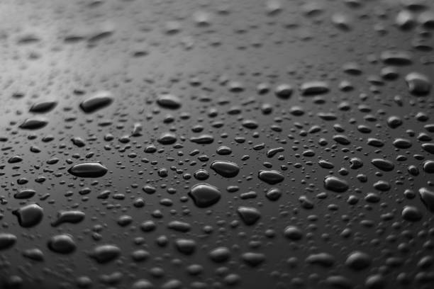 istock Rain or water drops different size on a black shiny car hood surface. Water droplets on dark iron surface and texture. Abstract background and water texture for design. 1724497262