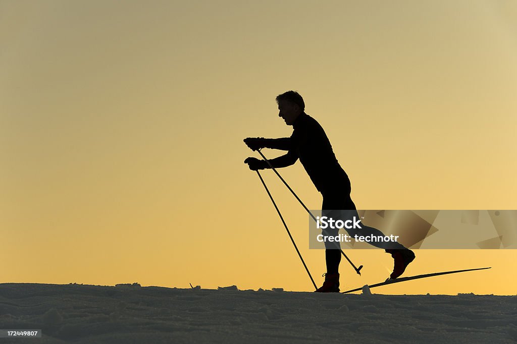 Silueta de una cruz país esquiador en la puesta de sol - Foto de stock de Elegancia libre de derechos