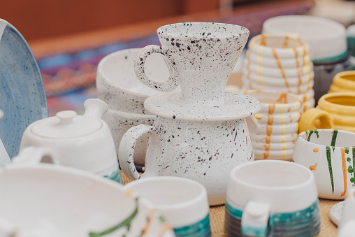 handmade ceramics, empty craft ceramic plates, mug, cup and bowls at a street fair or flea market or street Sunday market. Selective focus.