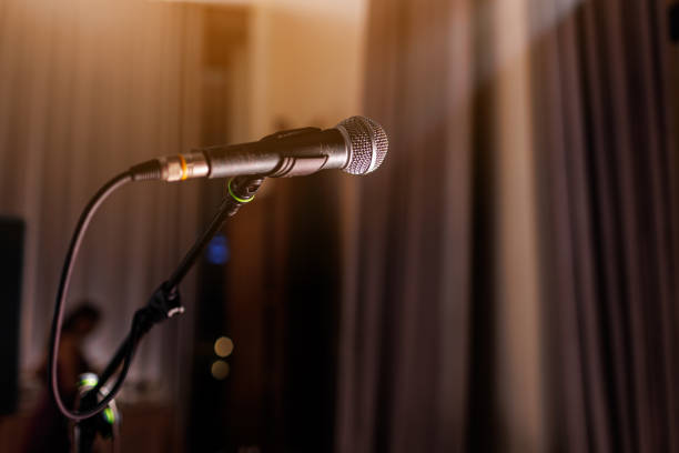 istock Microphone on stand on stage close up with searchlight light. Professional mic at concert hall or conference room, karaoke, night club, bar. Public events, festival, wedding. Copy space. 1724501988